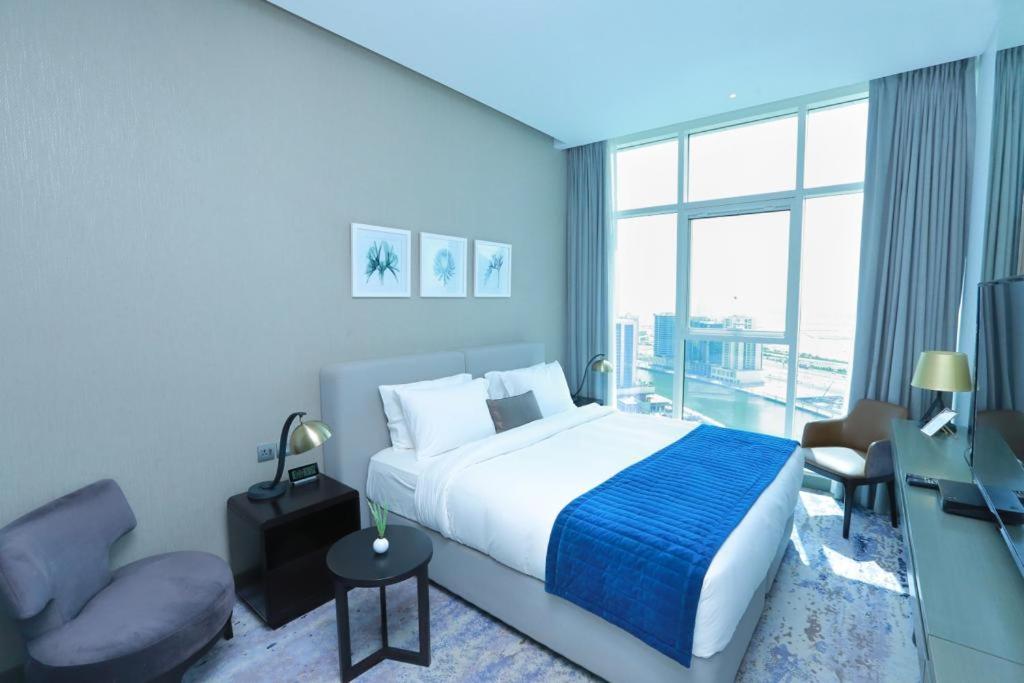 a bedroom with a bed and a chair and a window at DAMAC MAISON PRIVE in Dubai