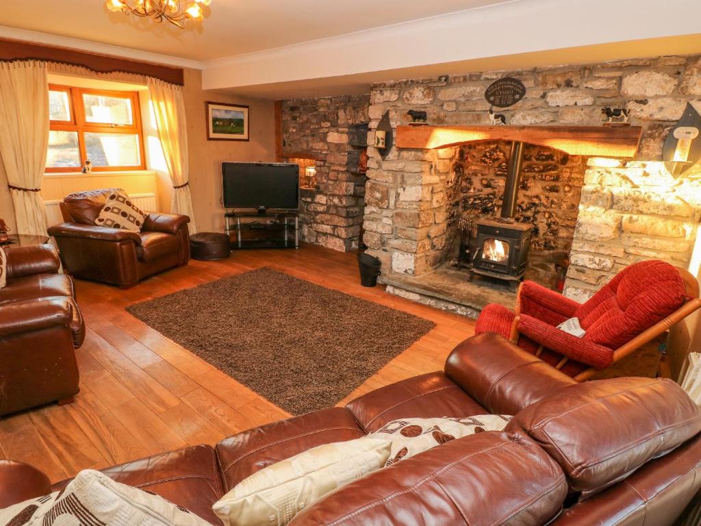 a living room with a couch and a stone fireplace at Pant Teg Farm in Kidwelly