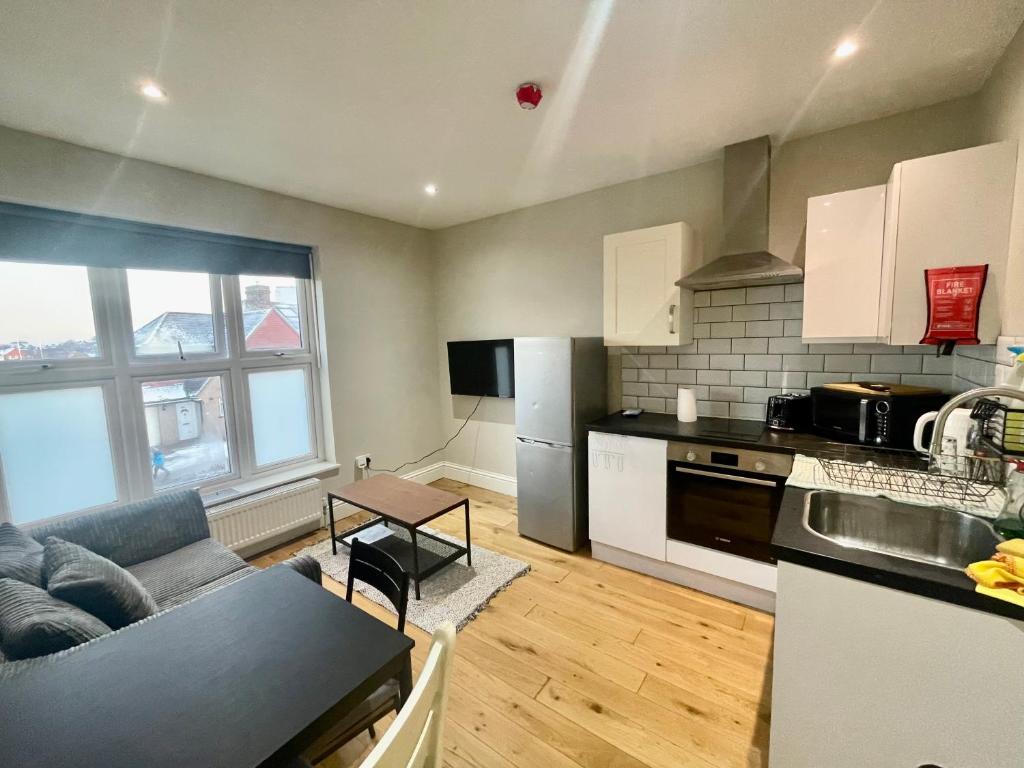 a kitchen and living room with a couch and a table at Cosy 1 bedroom flat! in London