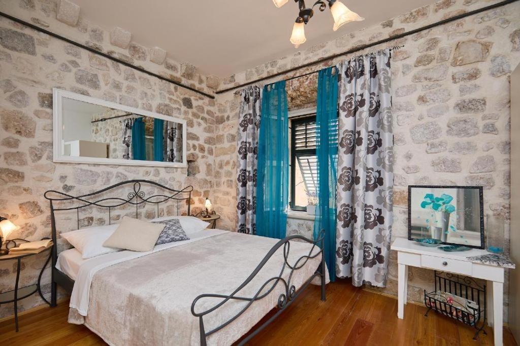 a bedroom with a bed and a stone wall at Festa Apartments in Dubrovnik