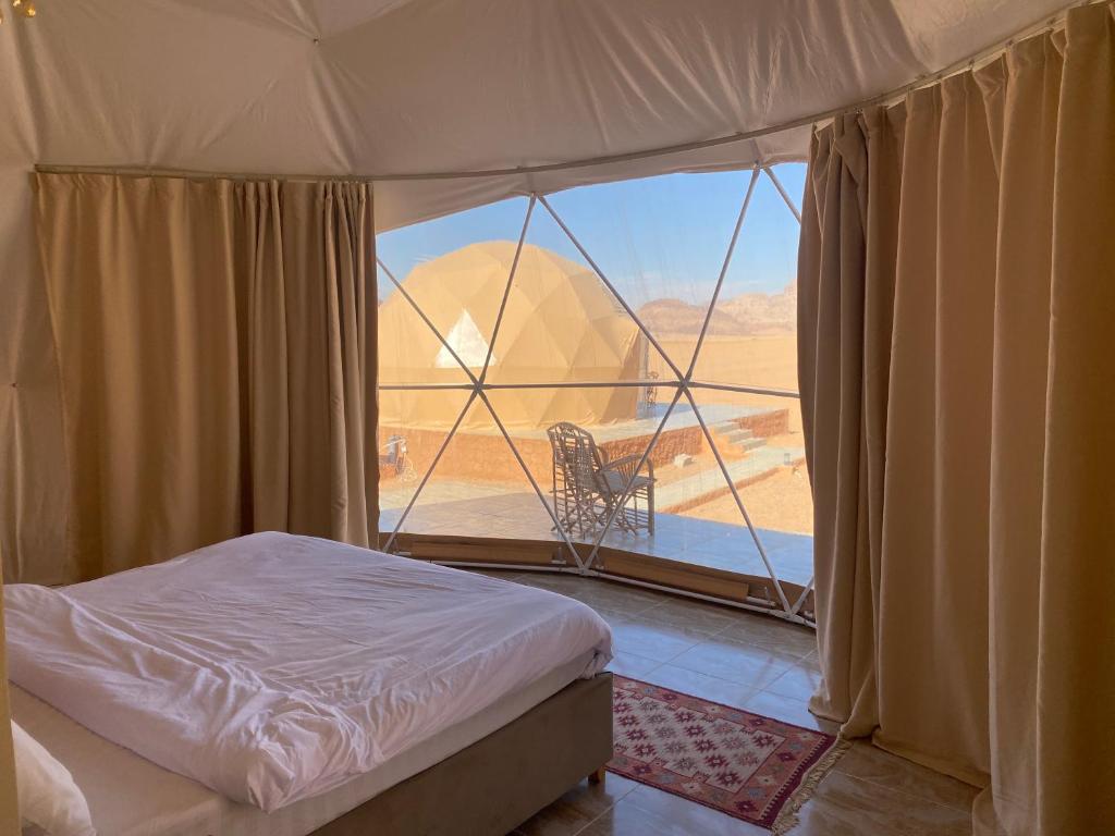 a bedroom with a bed and a view of a desert at Abdullah wadi rum camp in Wadi Rum
