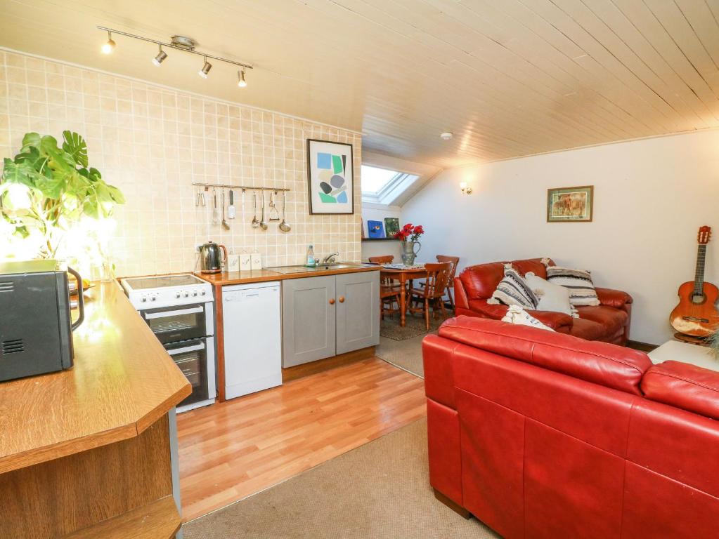 a living room with a red couch and a kitchen at Bracken Cottage in Okehampton
