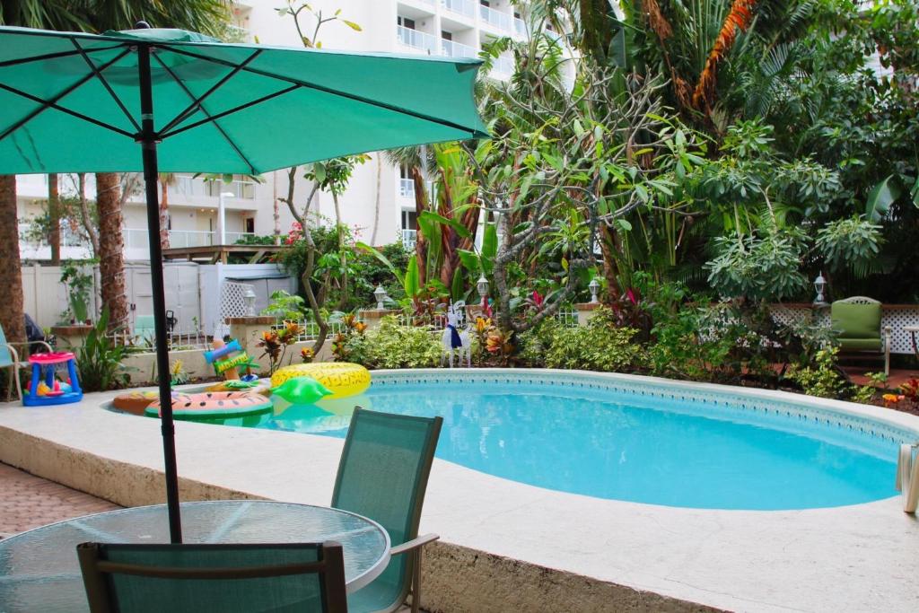 einen Tisch mit einem Sonnenschirm neben einem Pool in der Unterkunft Treasure Island Beach Retreat Sleeps Up To 8 in St Pete Beach