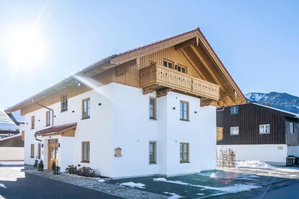 ein großes weißes Gebäude mit einem Holzdach in der Unterkunft Alpenrose Ferienwohnungen in Lenggries