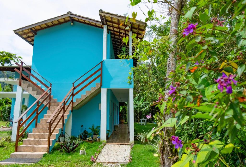 a blue house with stairs and flowers at Suítes da Barra in Ubatuba