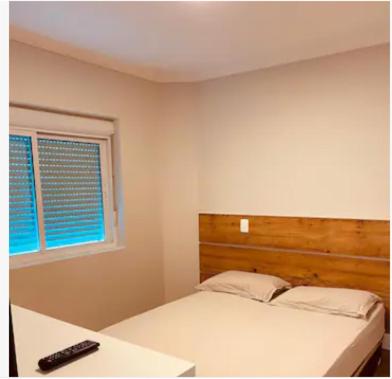 1 dormitorio con 1 cama con mando a distancia en Flat aconchegante, en Curitiba