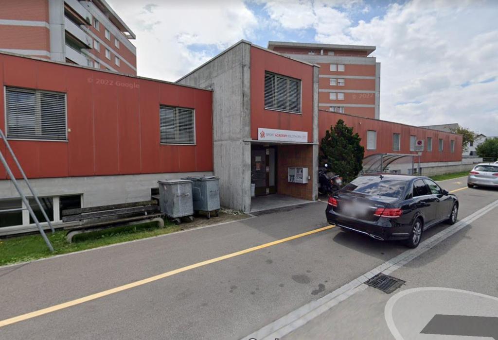 a car parked in a parking lot next to a building at HoStel Self Check-In Solothurn in Zuchwil