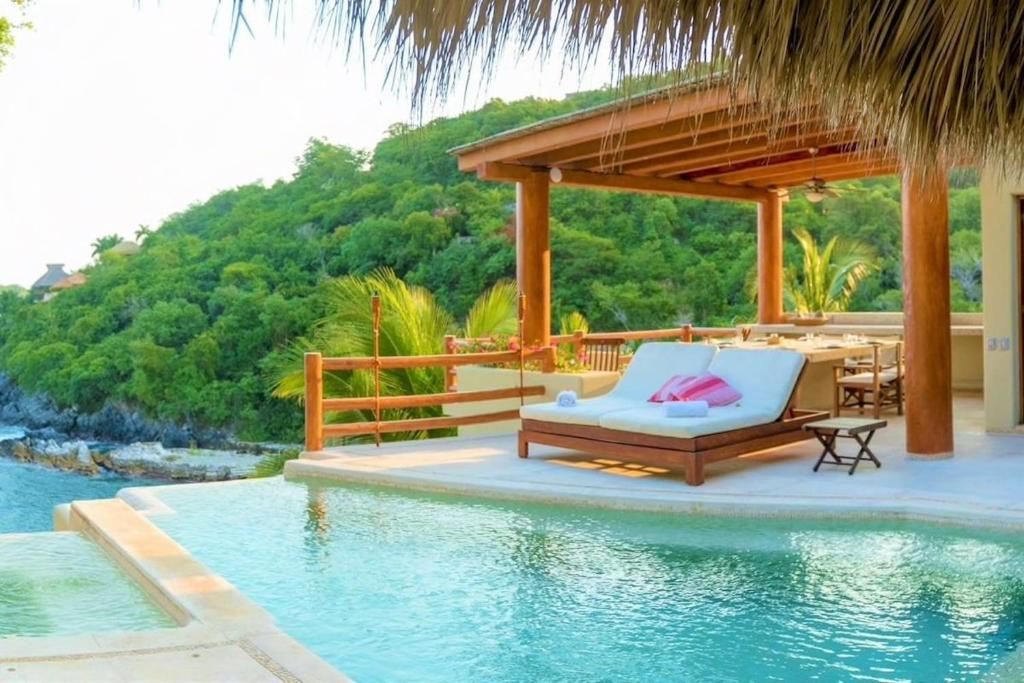 um pátio de resort com uma mesa e uma piscina em Villa Luna Kuku em Zihuatanejo
