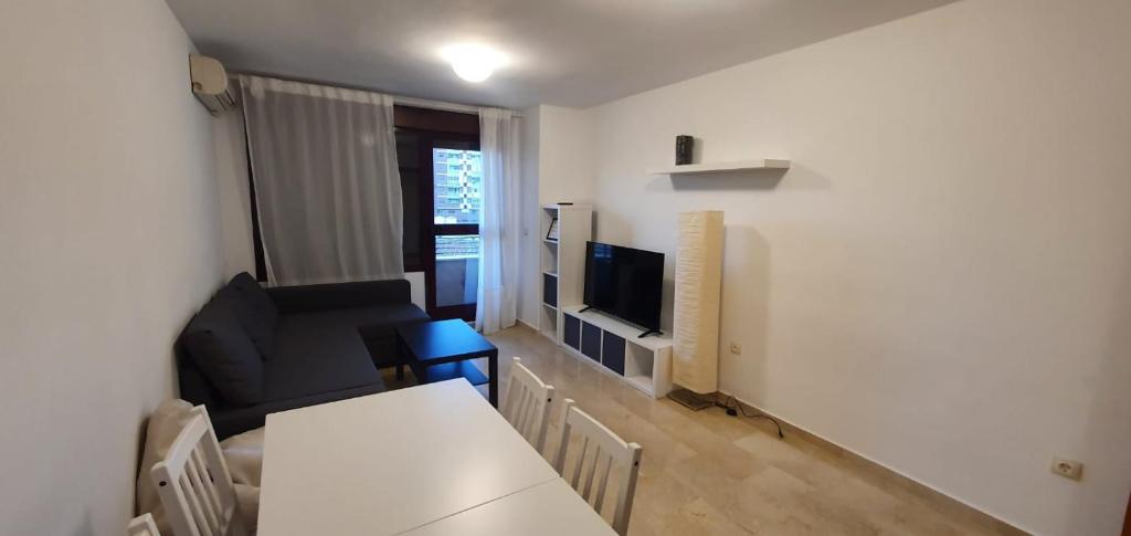 uma sala de estar com uma mesa, um sofá e uma televisão em Gran piso cerca Centro Comercial y Playa em Ceuta