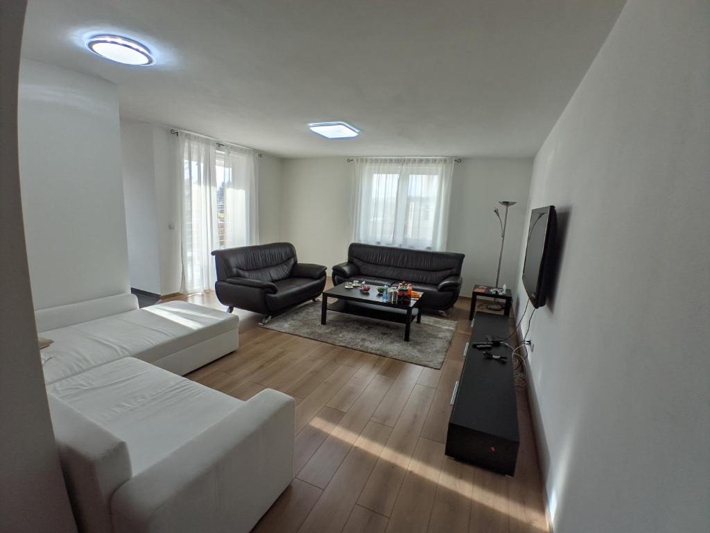 uma sala de estar com um sofá branco e uma televisão em Ika LuX apartmani 4* em Sjenica