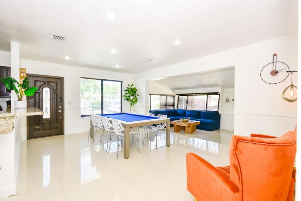 Una sala de estar con una mesa de ping pong y una silla naranja. en Five Bedroom Villa With POOL In Highland Lakes Near Aventura Mall, en Miami
