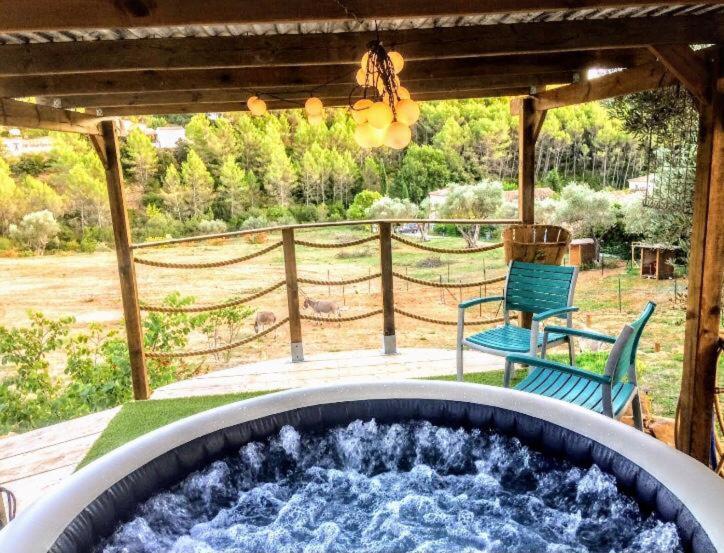 Un jacuzzi en un patio con dos sillas y una mesa. en Arche de Noé atypique, bohème , nature, piscine chauffée de Pâques à Toussaint , spa , sauna , loisirs, en Le Beausset