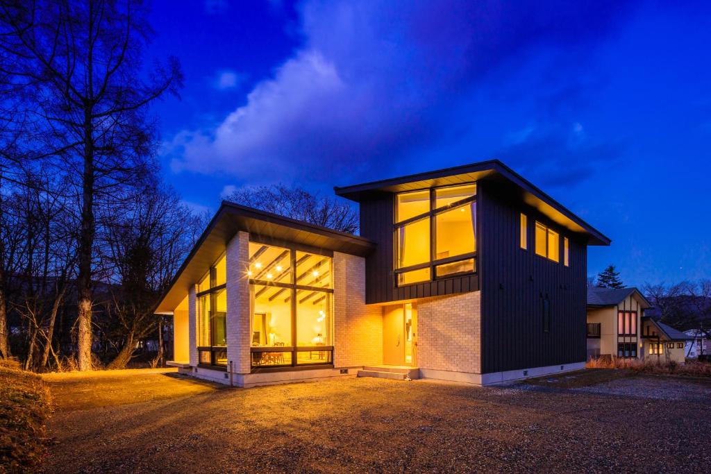 Casa con ventanas grandes en una entrada de noche en Hakuba Jolie Maison by Jade Group, en Hakuba