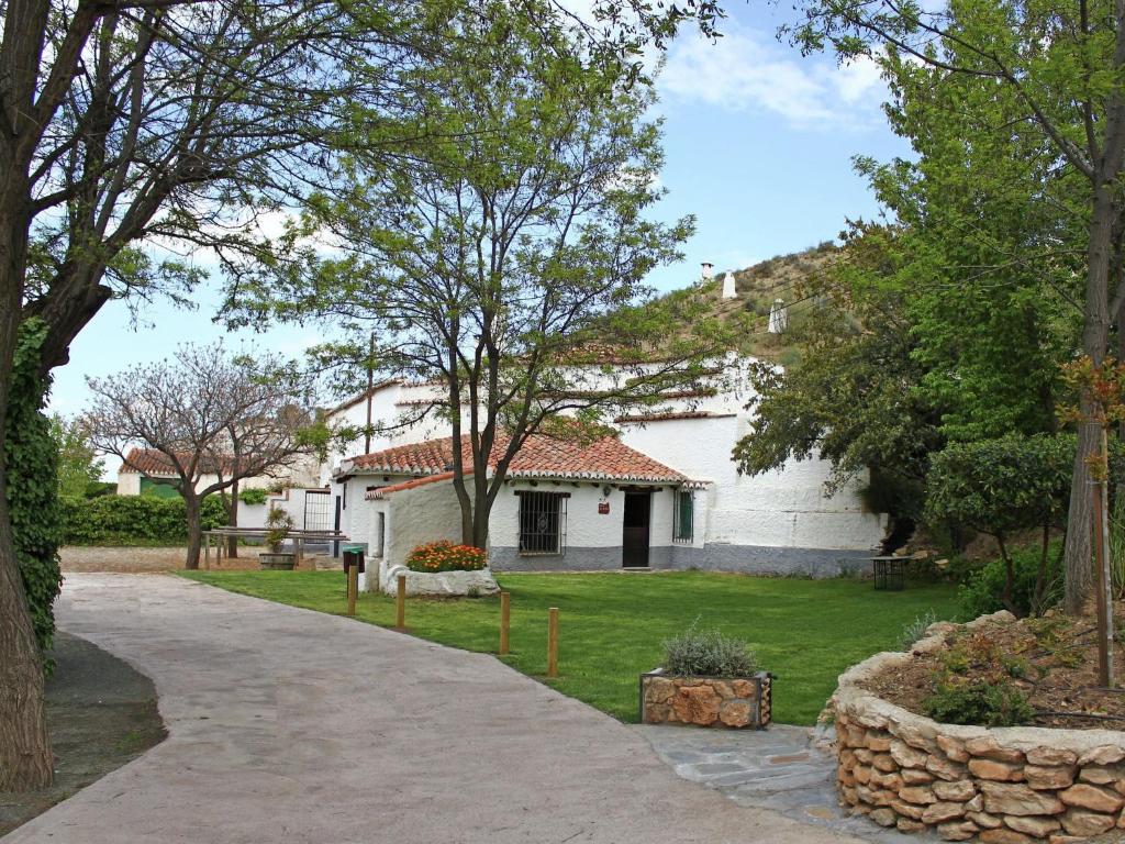a white house with a tree and a driveway at Rustic Cave House in Alcudia de Guadix with Pool in Alcudia de Guadix