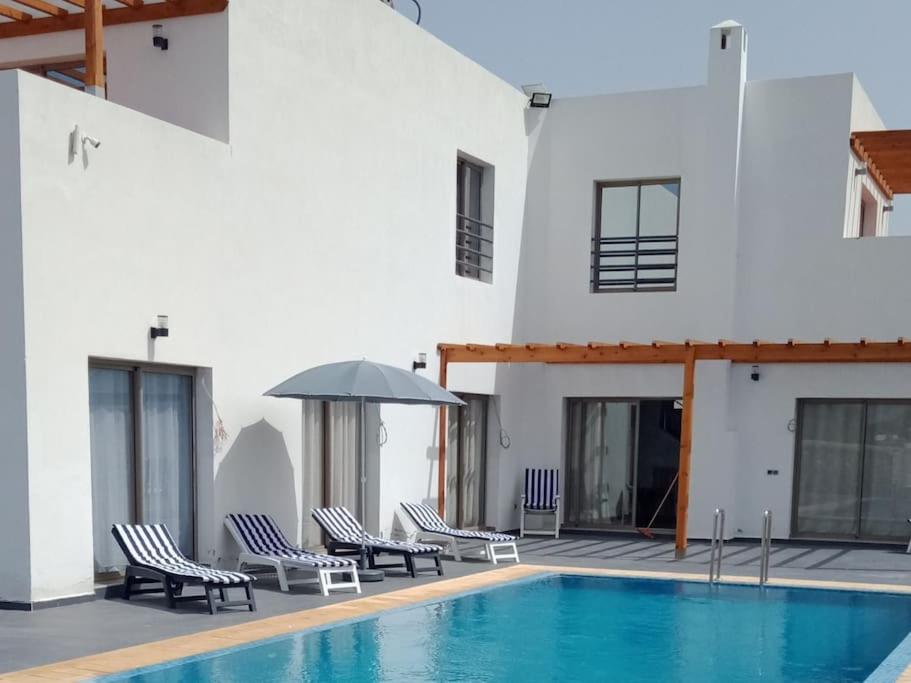 uma piscina com cadeiras e um guarda-sol ao lado de um edifício em Bidani Villa em Essaouira