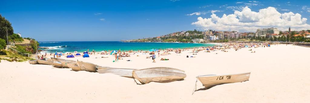 a group of people on a beach with the ocean at Coogee Beach House in Sydney