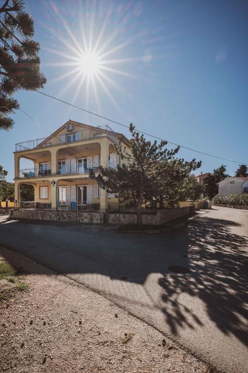 duży żółty dom ze słońcem na niebie w obiekcie Apartments in Klimno - Insel Krk 43356 w mieście Klimno