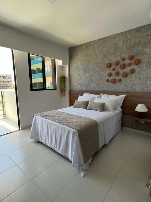 een slaapkamer met een groot wit bed en een raam bij Mana Beach Sol by Vivere Flats in Porto De Galinhas