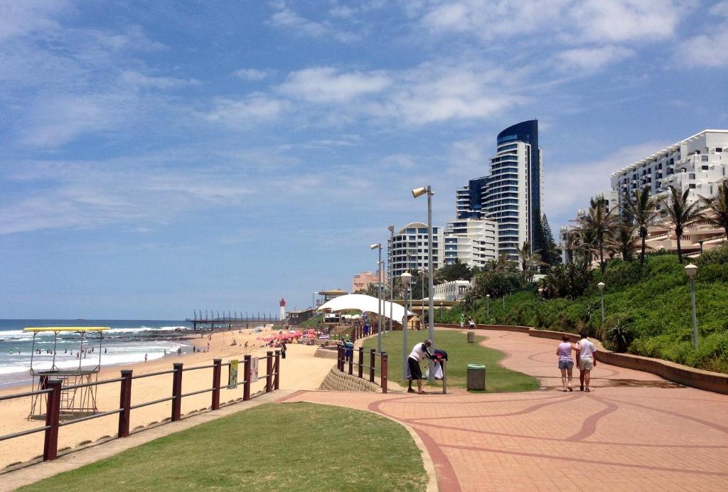 a beach with buildings and people walking on a sidewalk at 1 Licorna Beach in Durban