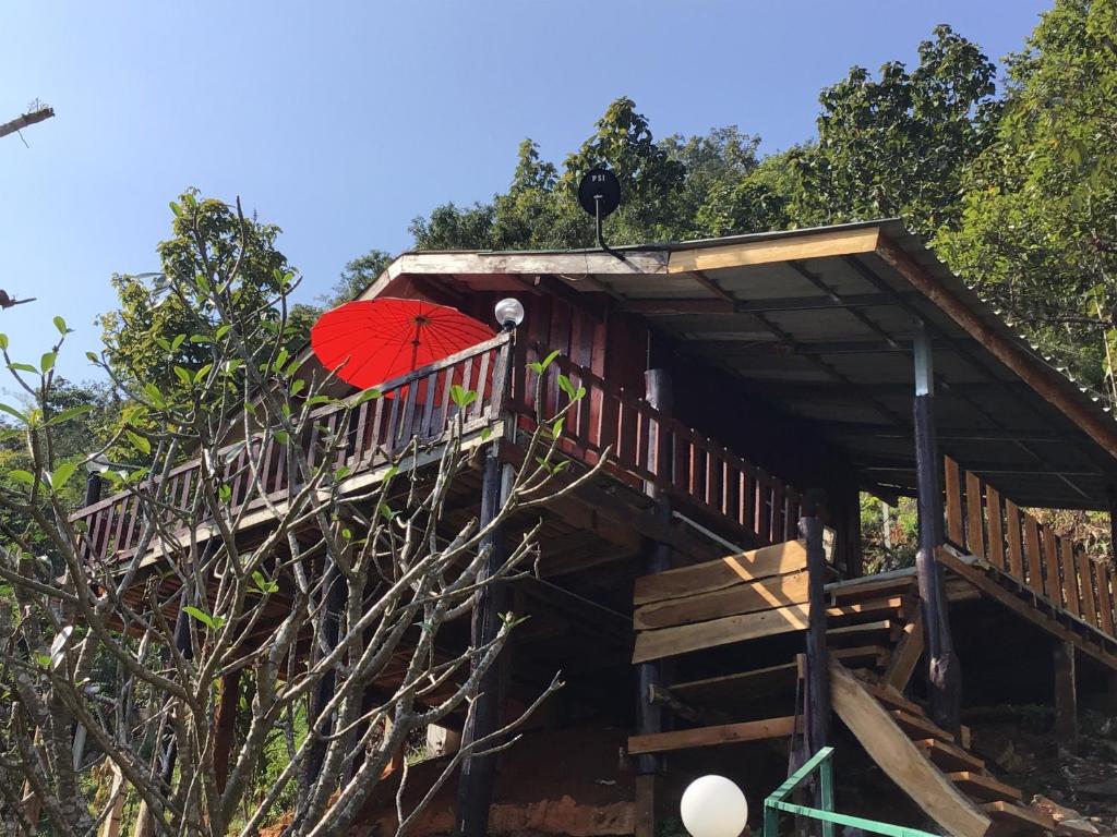 a person with a red umbrella sitting on a deck at Forest Guesthouse in Samoeng