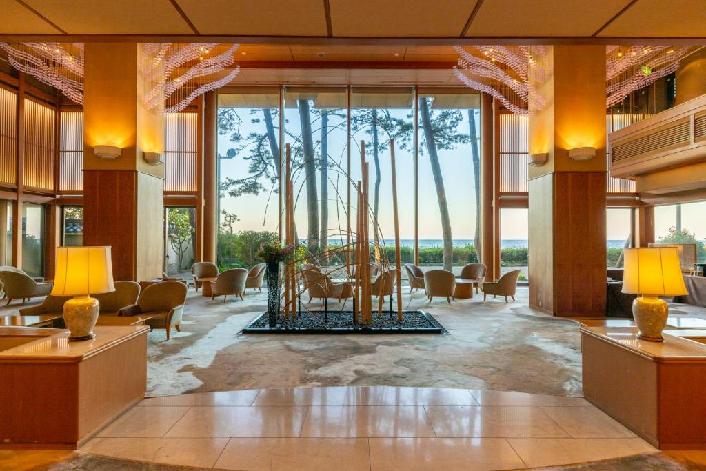 - un hall avec une table, des chaises et de grandes fenêtres dans l'établissement Kasuitei, à Yonago