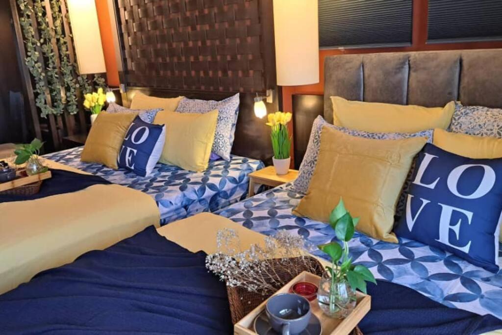 a bedroom with two beds with blue and yellow pillows at 6pax Homestay Resort Suite 1min to Sunway Pyramid in Petaling Jaya