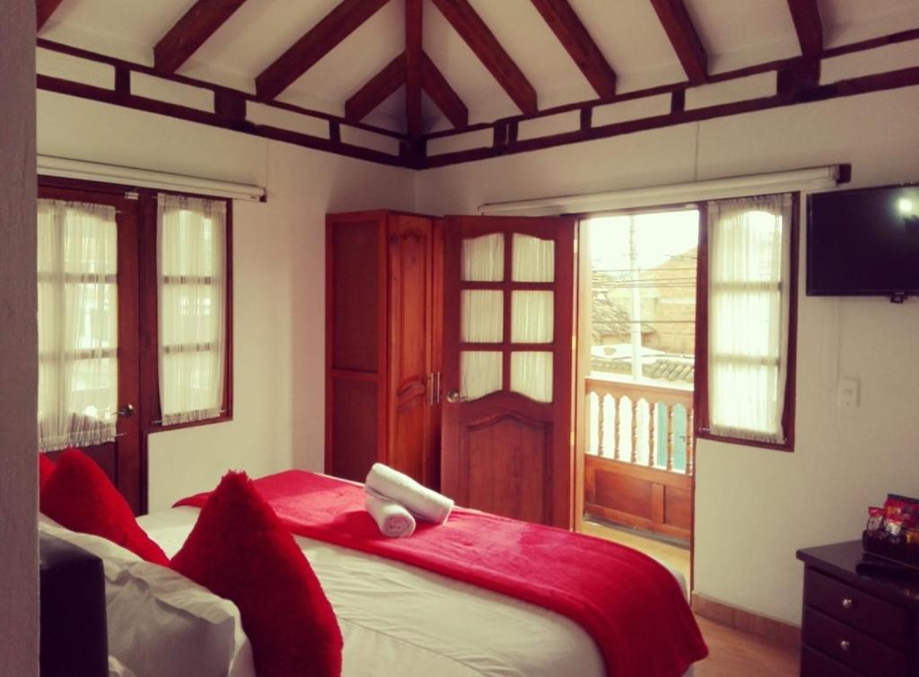 a bedroom with a large bed with a red blanket at Hospederia Sandaned in Villa de Leyva