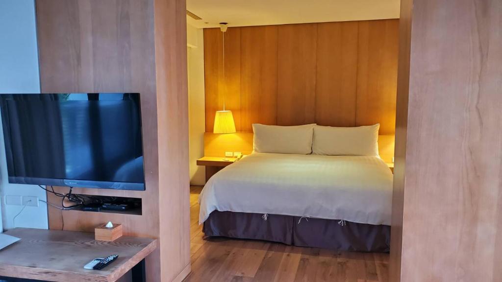 a bedroom with a bed and a flat screen tv at Fu Wan Cafe Villa in Donggang