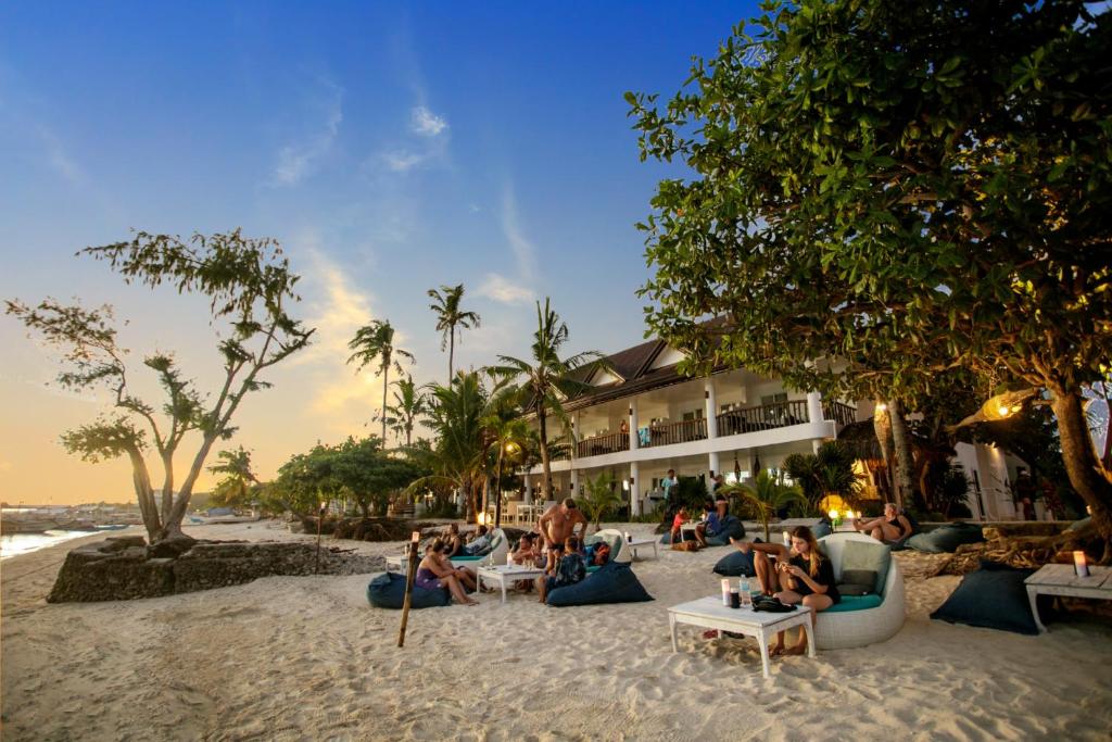 Ocean Vida Beach and Dive Resort في Daanbantayan: مجموعة من الناس جالسين على الرمال على الشاطئ