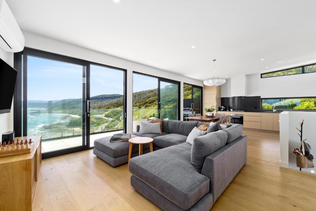 a living room with a couch and large windows at Glassy Point - 360 degree views in Wye River