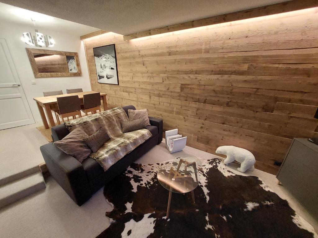 a living room with a couch and a wooden wall at 40m2 - Ski aux pieds - La Tania - Parking couvert in La Perrière