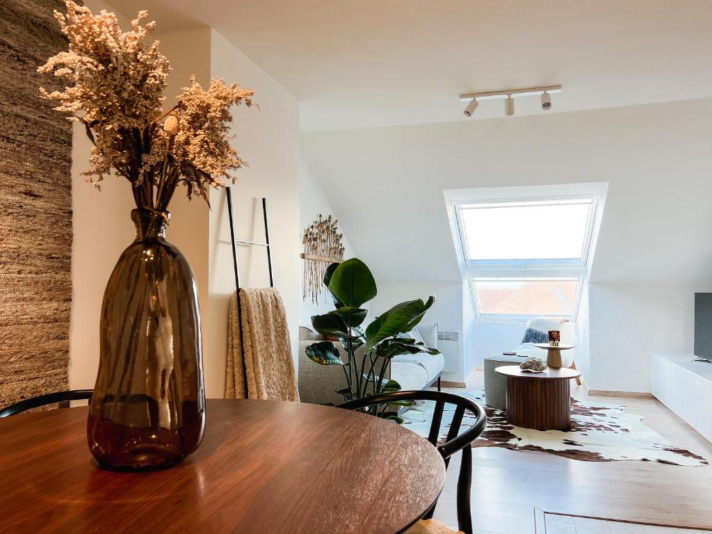 un jarrón con flores sentado en una mesa de madera en Stijlvol appartement aan het strand van Oostduinkerke, en Oostduinkerke