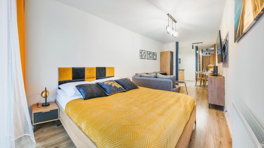 Apartament Studio z parkingiem 22 C Perłowa Przystań - Holiday City في كولوبرزيغ: غرفة نوم بسرير كبير مع بطانية صفراء