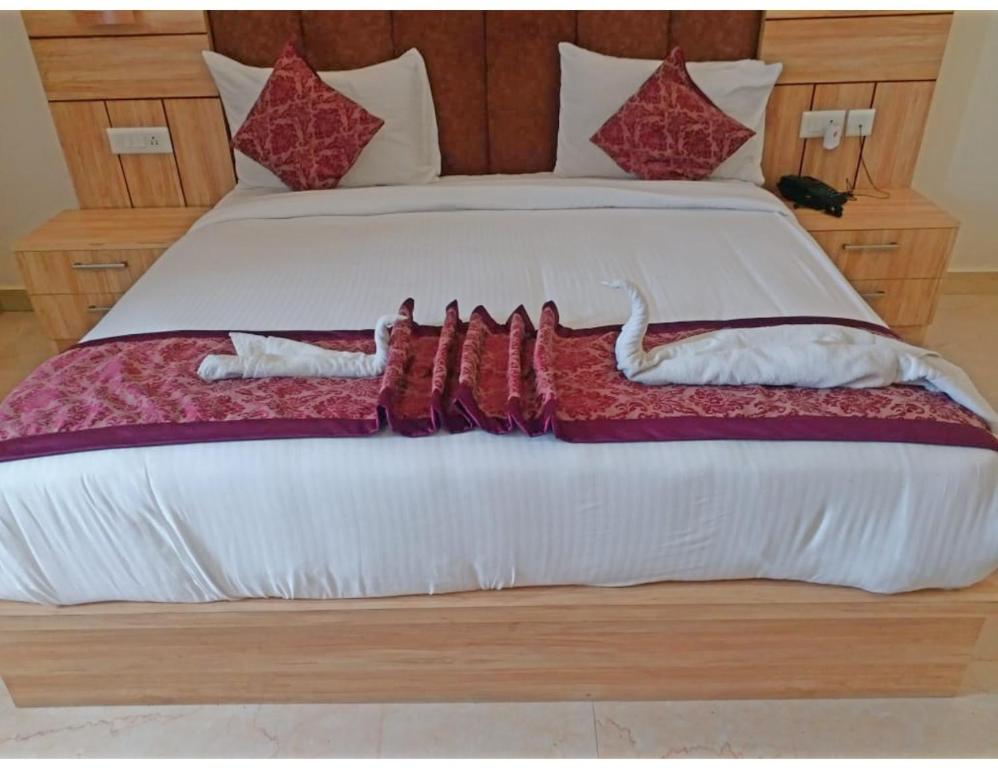 a bed with white sheets and red pillows on it at Hotel Paras Inn, Lucknow in Lucknow