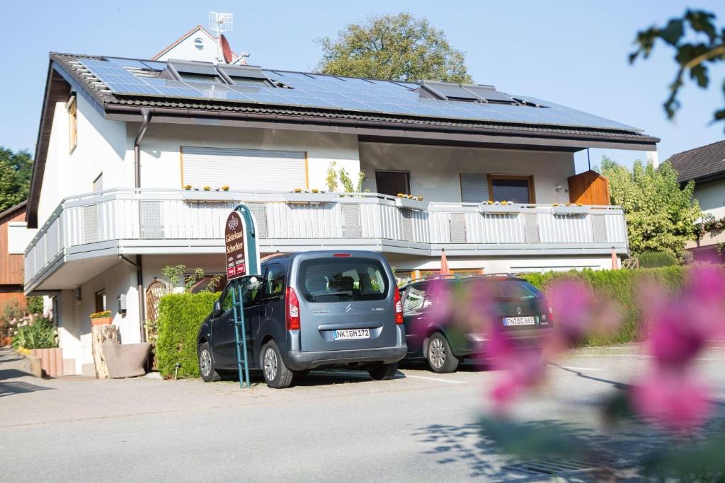 dos autos estacionados en un estacionamiento frente a una casa en Gästehaus Schechter, en Uhldingen-Mühlhofen