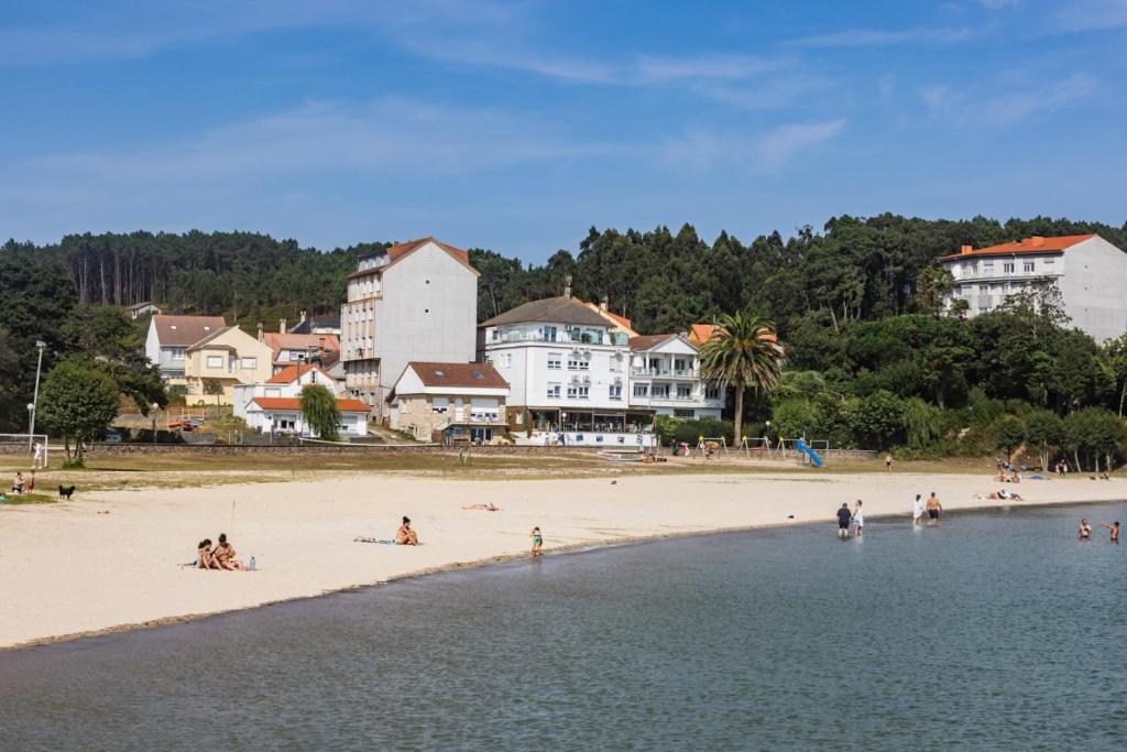un grupo de personas en una playa cerca del agua en Apartamentos Playa de Camariñas, en Camariñas