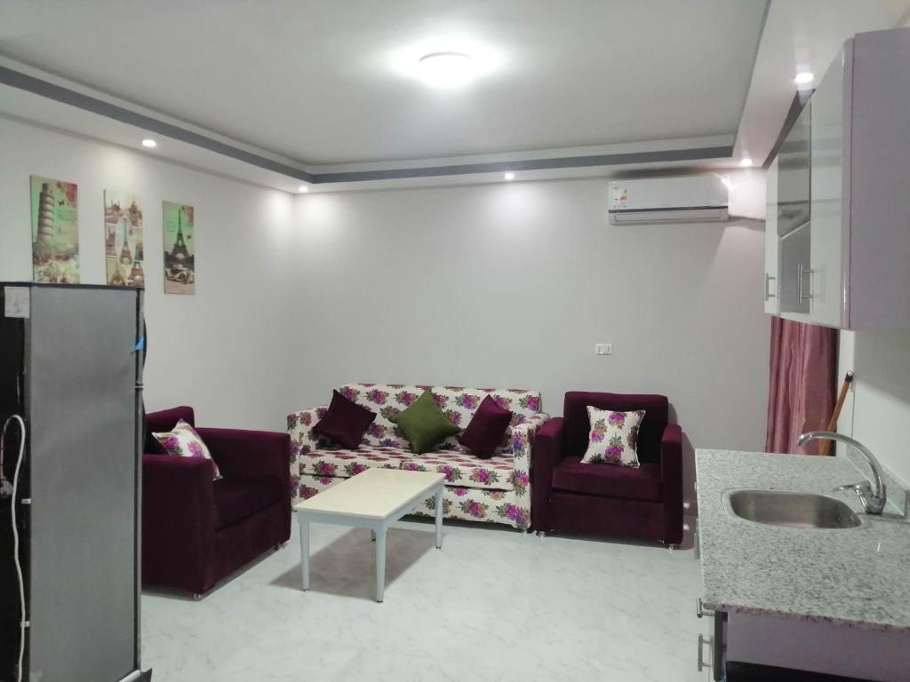 sala de estar con 2 sofás morados y cocina en 302 A, en Hurghada