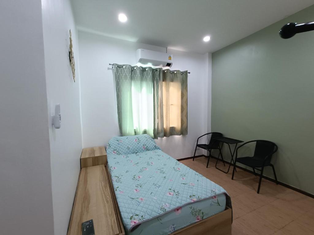 a small room with a bed and two chairs at Merit courtyard Suvarnaphumi HOUSE in Lat Krabang