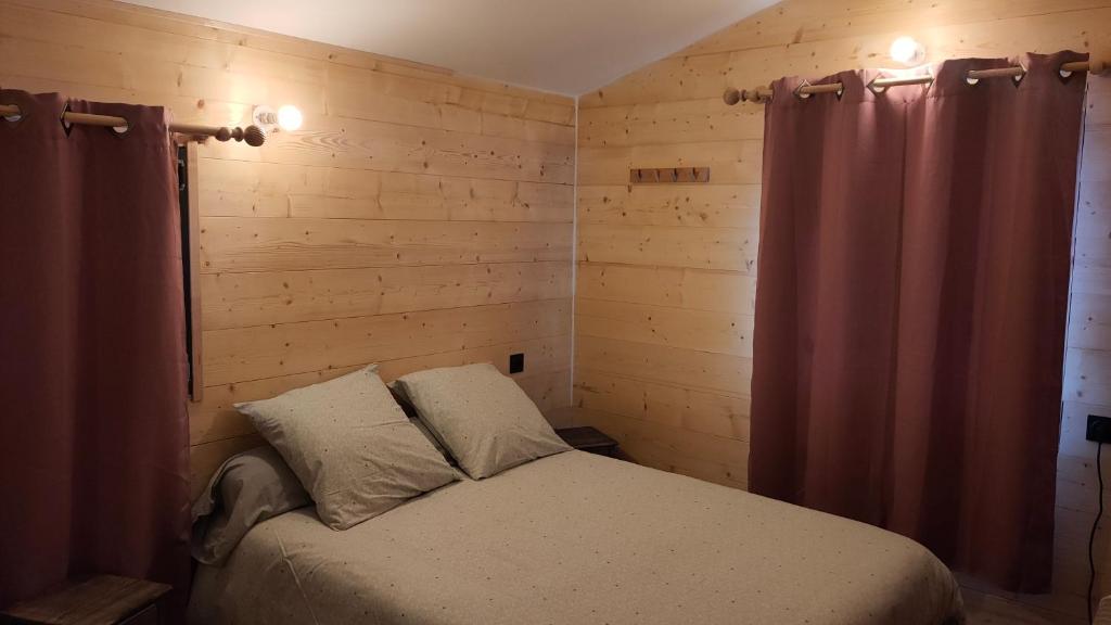 um quarto com uma cama num quarto com paredes de madeira em La tanière du lac d Aiguebelette em Lepin-le-Lac