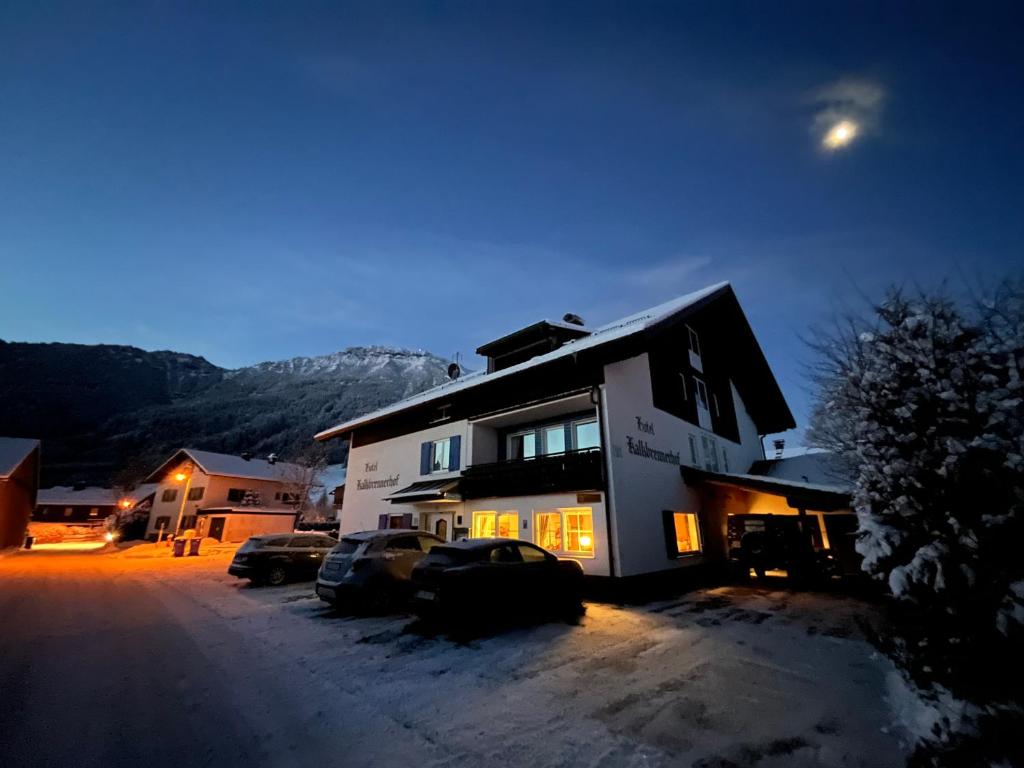 een huis met 's nachts in de sneeuw geparkeerde auto's bij Hotel-Garni Kalkbrennerhof in Pfronten