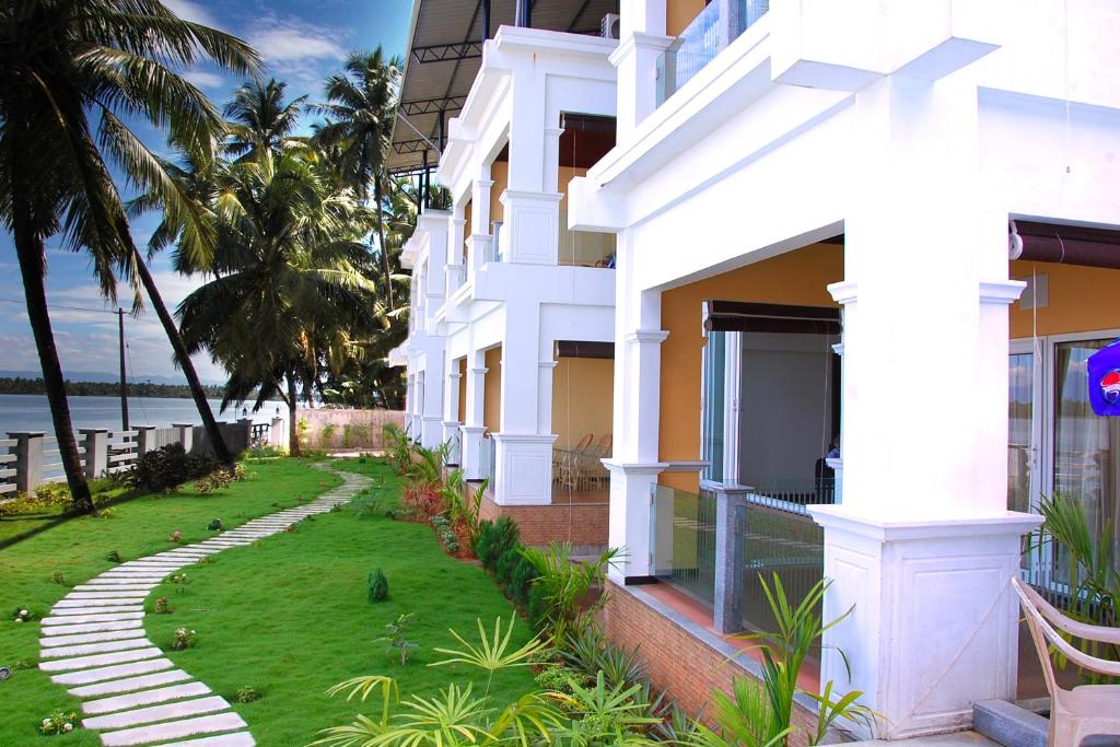 een wit gebouw met een pad langs de oceaan bij Blue Waters in Kundapura
