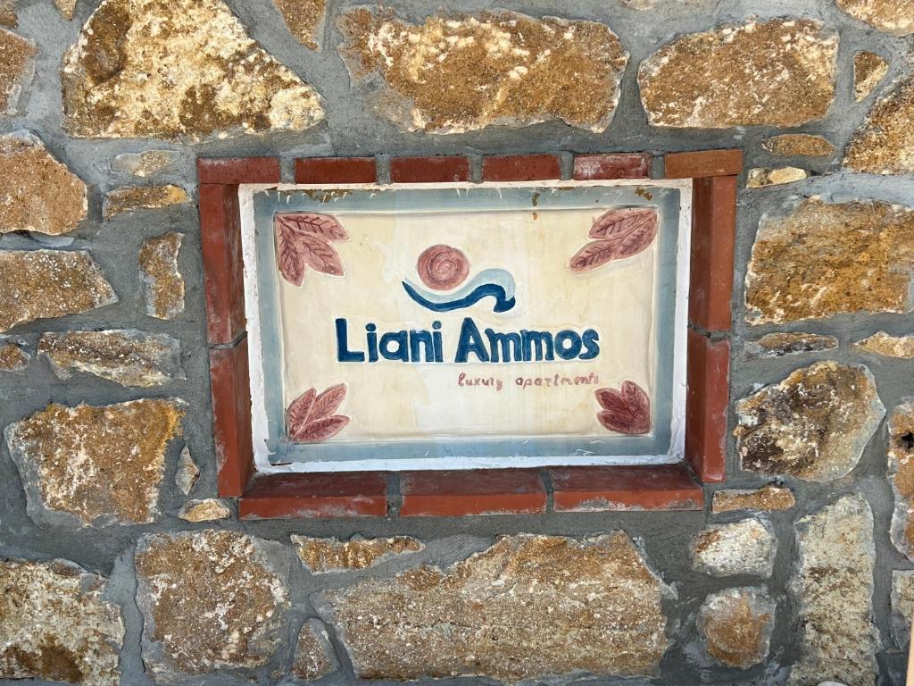 a sign on the side of a stone wall at Liani Ammos in Ammouliani