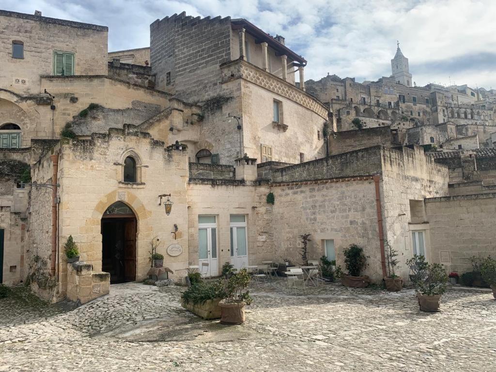 an old stone building with a mountain in the background at Thymus Residence nei Sassi in Matera