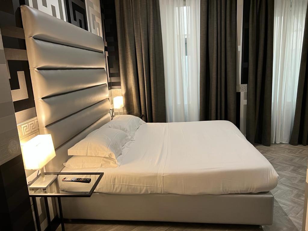 um quarto com uma grande cama branca e uma mesa lateral. em The One Firenze em Florença