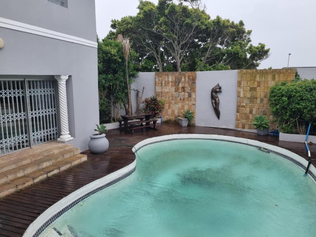 a swimming pool in a backyard with a wooden deck at Bunitrix Guesthouse in Summerstrand