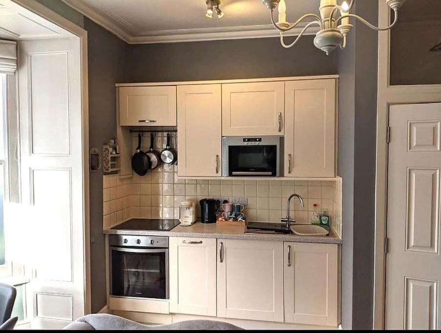een keuken met witte kasten en een magnetron bij Beautiful Ground floor apartment with Parking, Exeter in Exeter