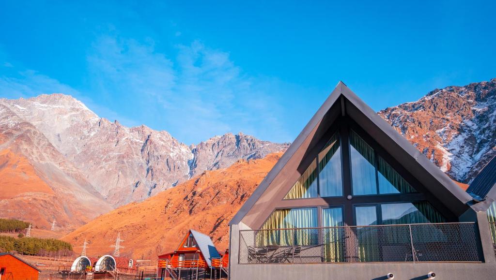 un edificio con montagne sullo sfondo di Kazbegi View Cottages a Kazbegi