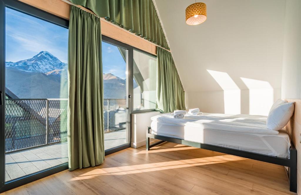 a bedroom with a bed and a large window at Kazbegi View Cottages in Stepantsminda