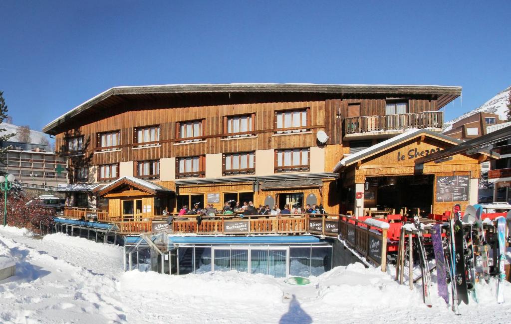 a ski lodge with people sitting outside of it in the snow at Hotel le Sherpa in Les Deux Alpes