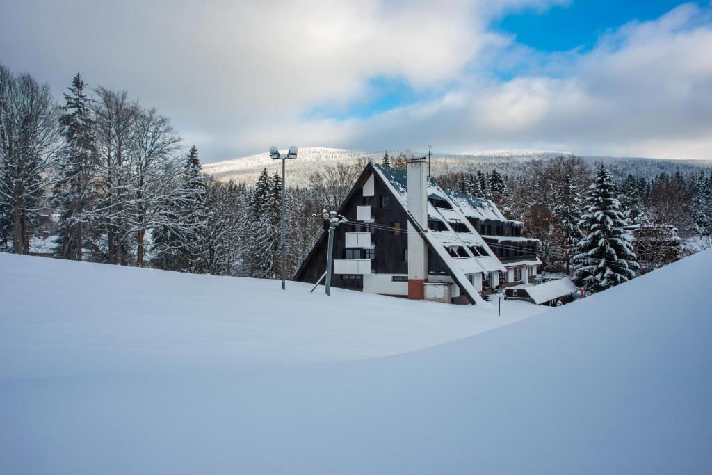 a house on top of a snow covered slope at Wellness Hotel Šedý Vlk in Harrachov